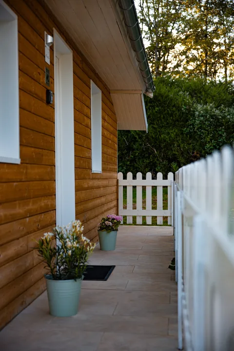 L'entrée du chalet, son bardage en bois et ses pots de fleurs