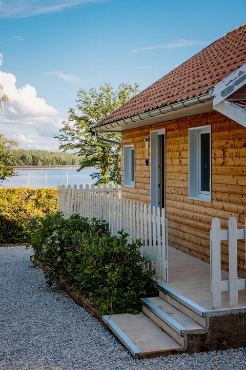 Le chalet en bois et sa barrière blanche, le bassin en arrière-plan