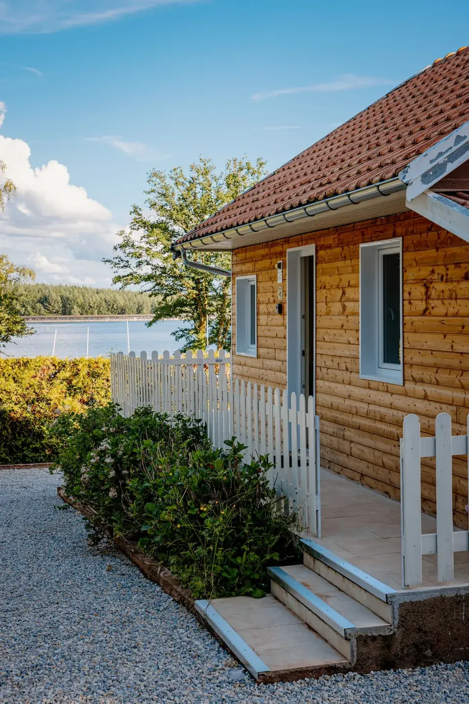 Le chalet en bois et sa barrière blanche, le bassin en arrière-plan