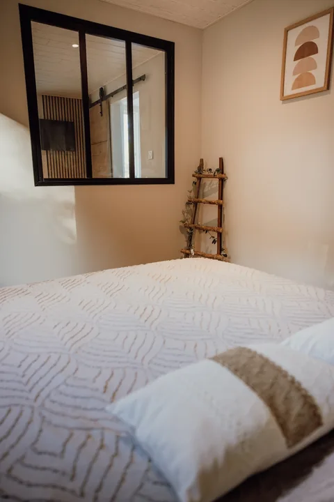 Le lit sous la verrière noire de la chambre