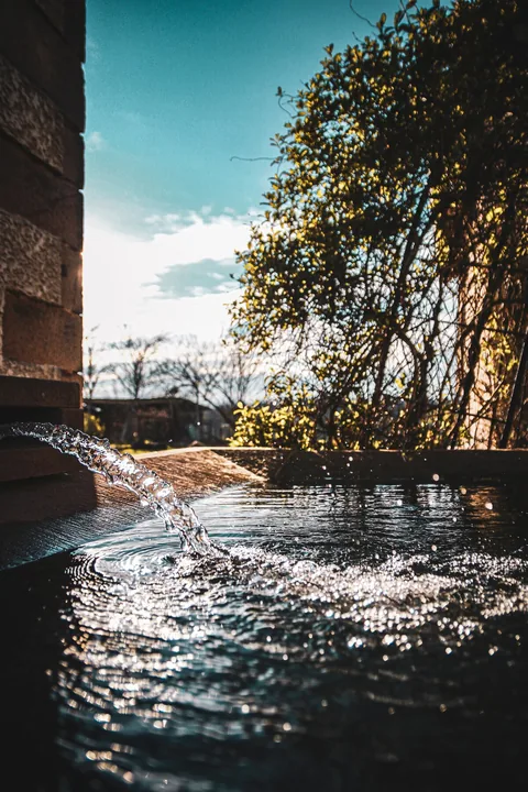 Wasser, das im Sonnenlicht in das Becken sprudelt
