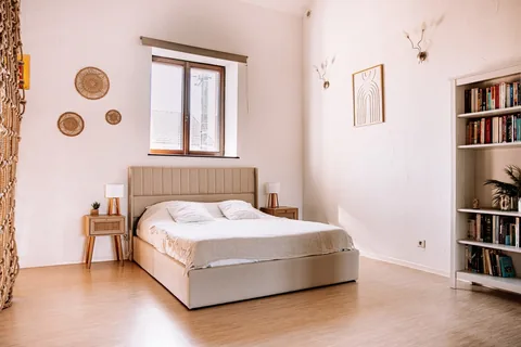 Das Bett vor dem Bücherregal, unter dem Fenster