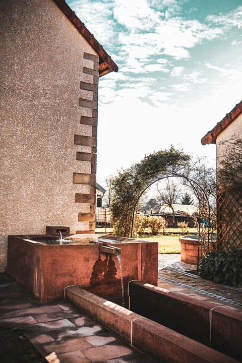 Der Brunnen aus Vogesensandstein neben dem Haus